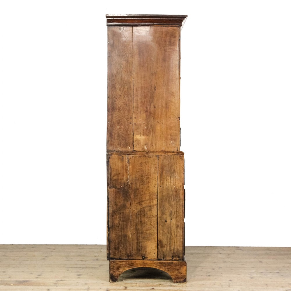 A nineteenth-century two-part oak housekeepers cupboard featuring twin panelled upper doors above two short and three long drawers with brass hardware. View XI