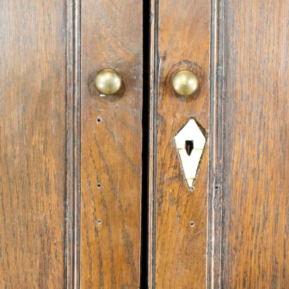 A nineteenth-century two-part oak housekeepers cupboard featuring twin panelled upper doors above two short and three long drawers with brass hardware. View XVIII
