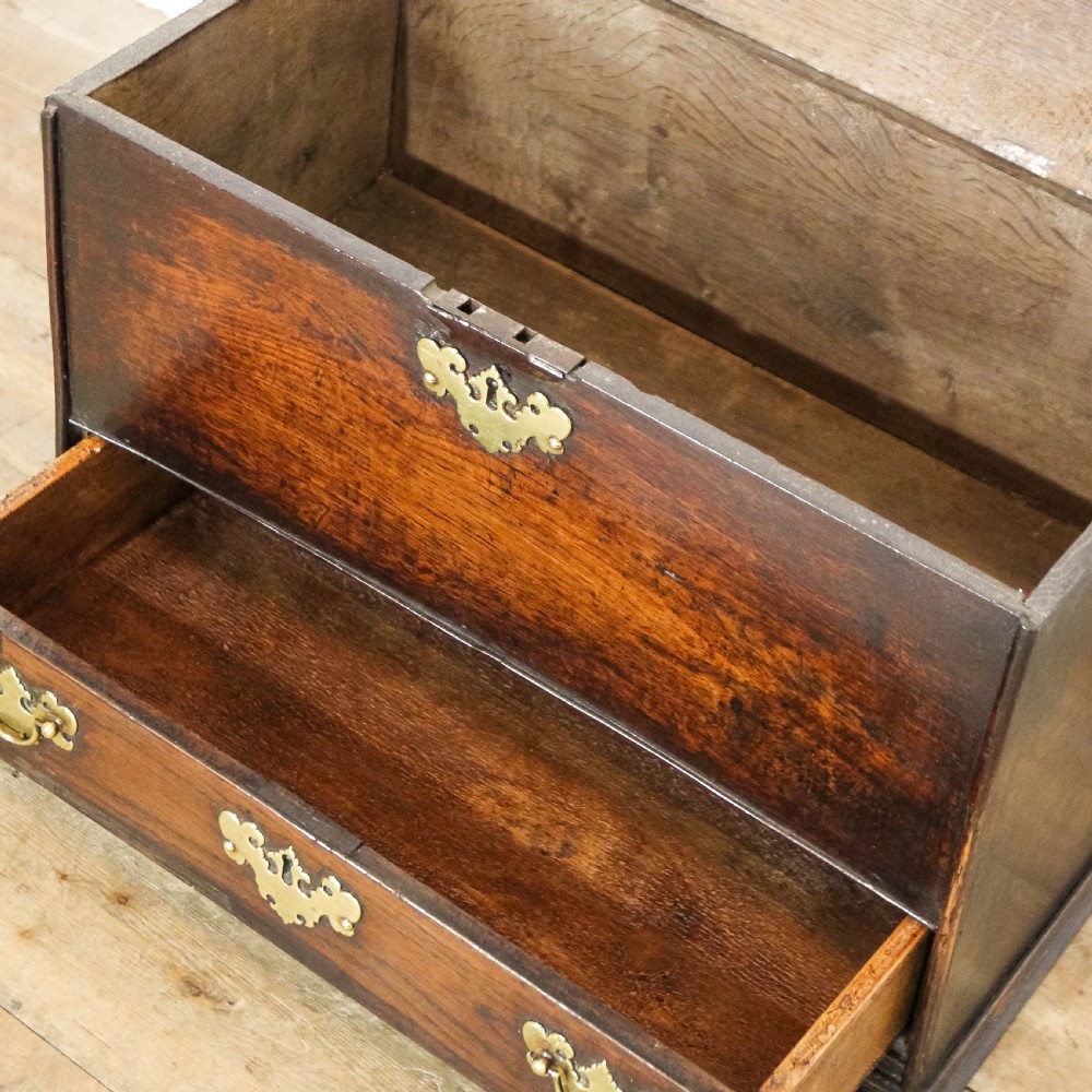 An antique dark oak coffer bach featuring a top hinged lid, a single lower drawer, and decorative brass escutcheons with swan-neck handles. View IX