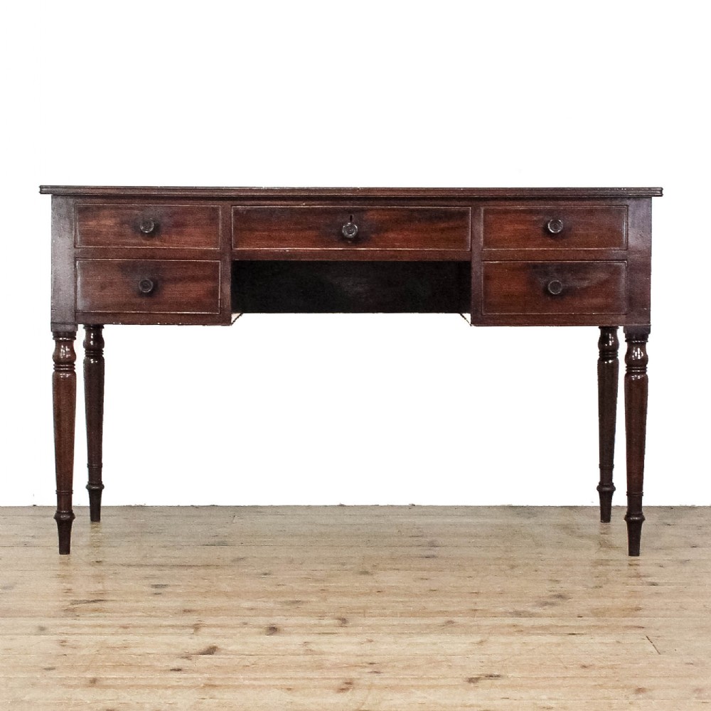 An antique dark mahogany writing desk featuring five drawers with turned wooden knobs and slender turned tapering legs.