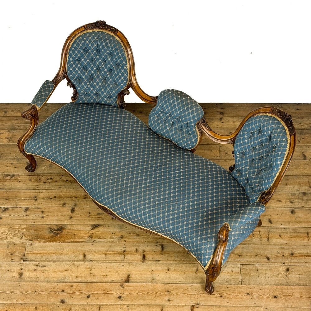 A Victorian carved walnut settee with double button-tufted balloon backrests and blue patterned fabric upholstery. View II