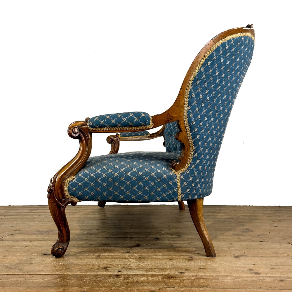 A Victorian carved walnut settee with double button-tufted balloon backrests and blue patterned fabric upholstery. View IV