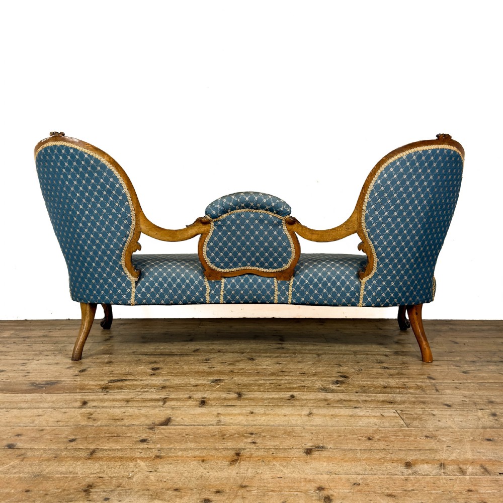 A Victorian carved walnut settee with double button-tufted balloon backrests and blue patterned fabric upholstery. View V
