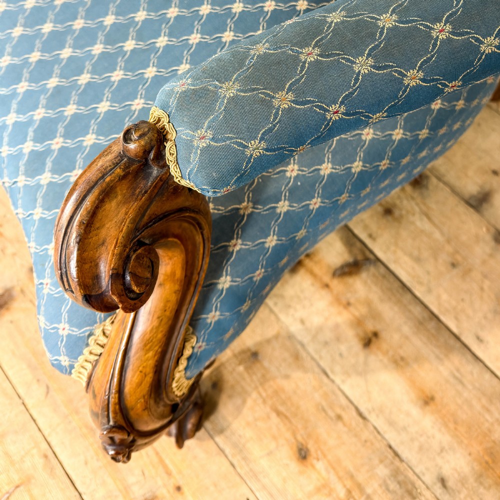 A Victorian carved walnut settee with double button-tufted balloon backrests and blue patterned fabric upholstery. View VI