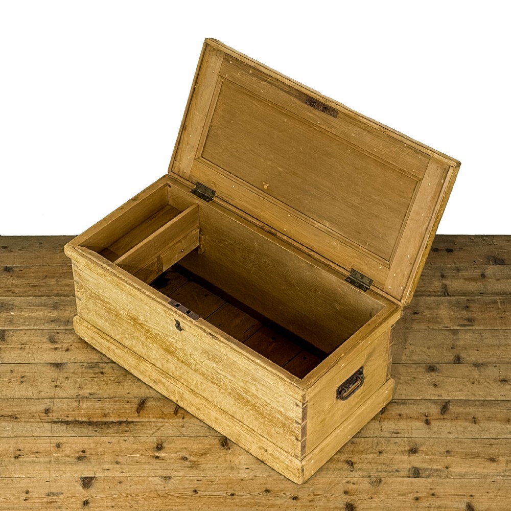 A rectangular natural pine blanket box featuring hand-cut dovetail joints, a hinged top lid, a moulded plinth base, and a central metal escutcheon. View IV