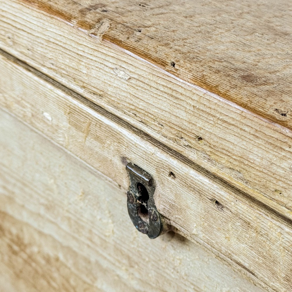 A rectangular natural pine blanket box featuring hand-cut dovetail joints, a hinged top lid, a moulded plinth base, and a central metal escutcheon. View X