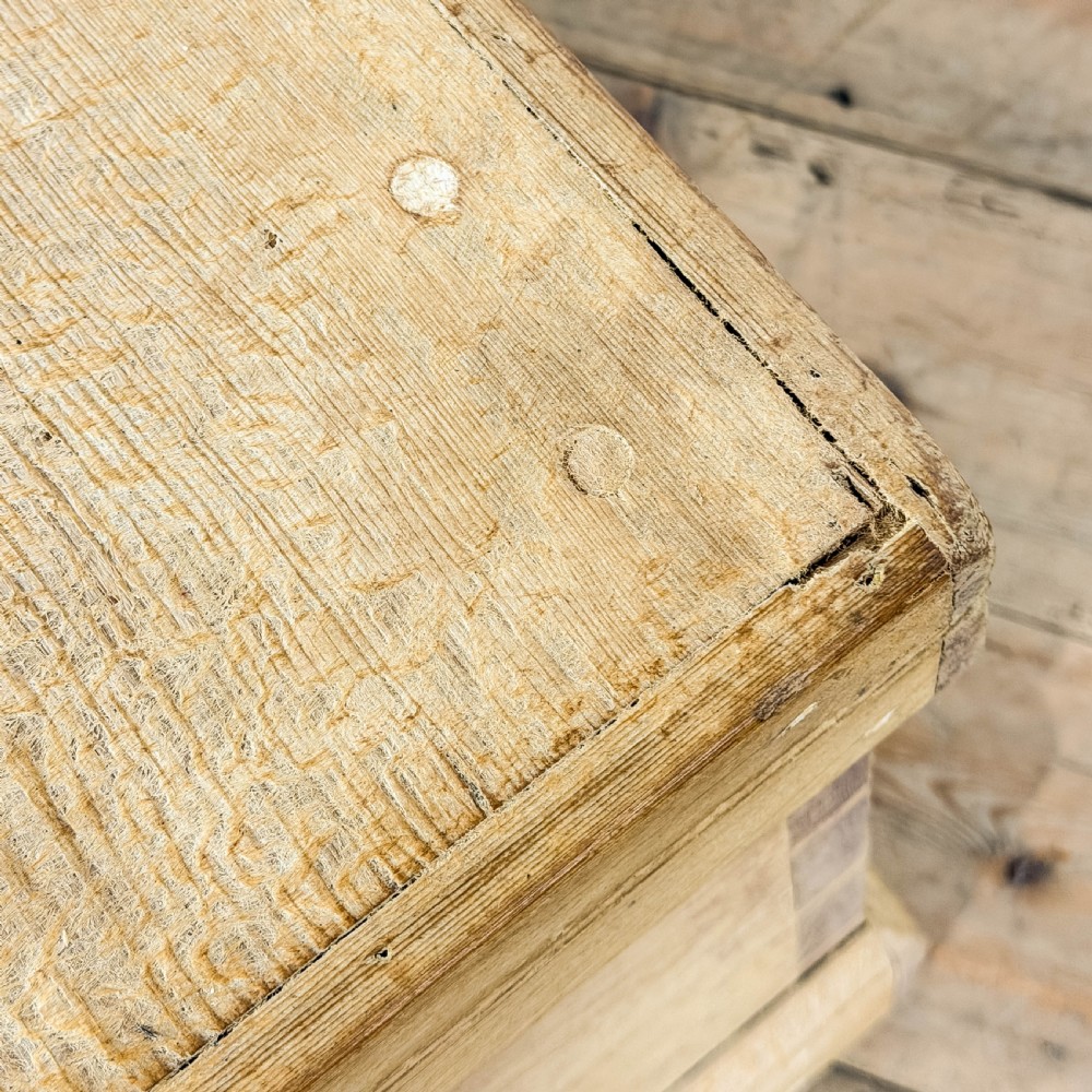 A rectangular natural pine blanket box featuring hand-cut dovetail joints, a hinged top lid, a moulded plinth base, and a central metal escutcheon. View XI