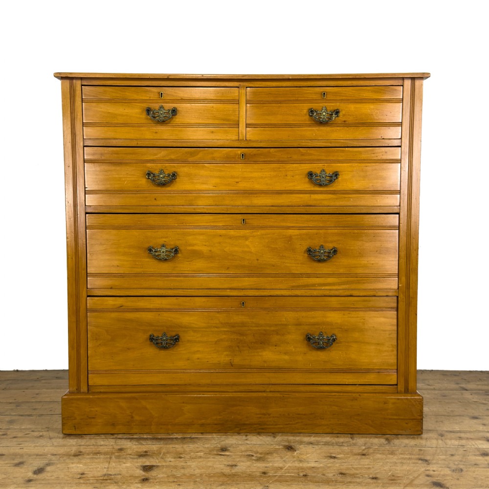 An Edwardian satinwood chest of drawers with two short drawers over three long drawers, featuring brass drop handles and a plinth base.