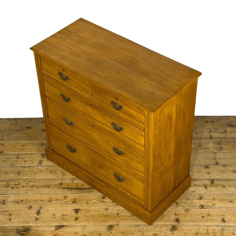 An Edwardian satinwood chest of drawers with two short drawers over three long drawers, featuring brass drop handles and a plinth base. View IV