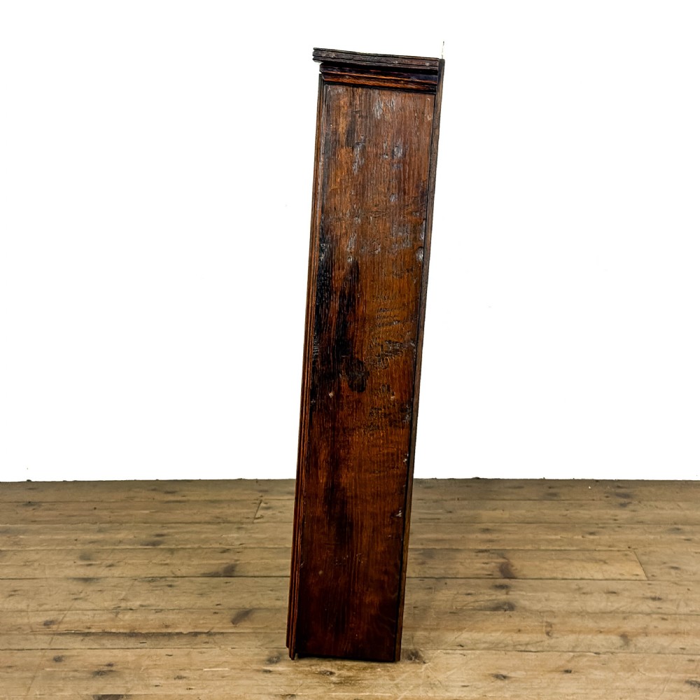A dark brown oak two-tier wall-hanging shelf unit featuring a scalloped top frieze and vertical planked backboard. View IV