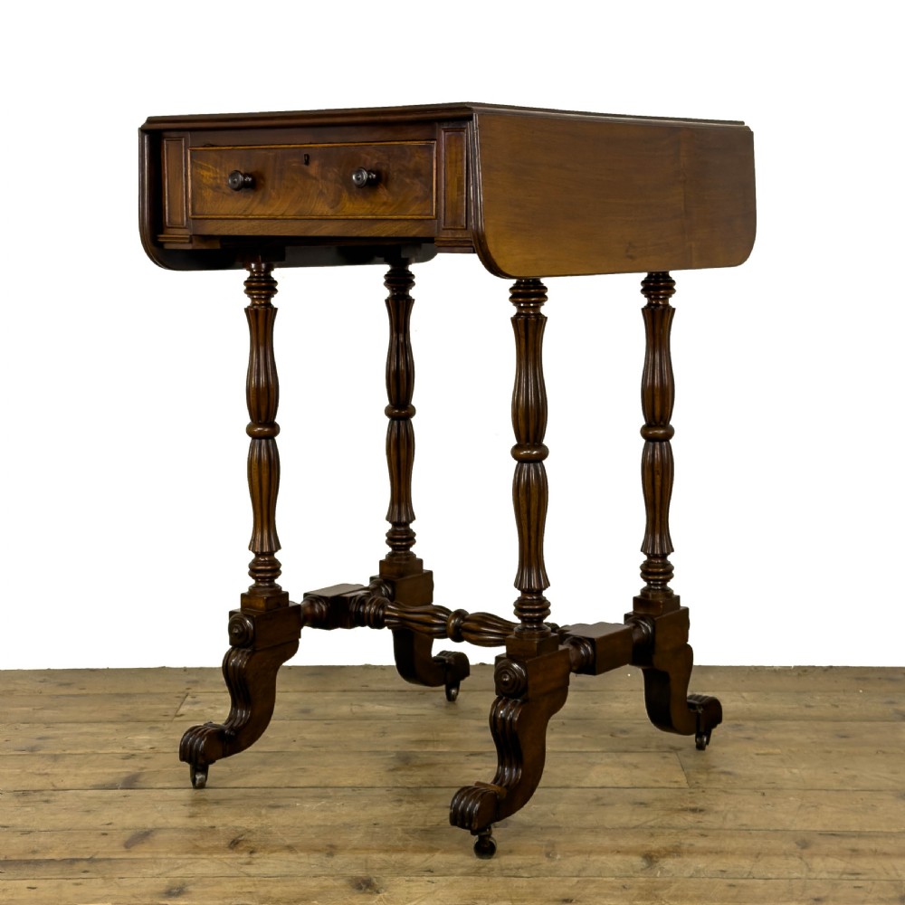 An antique Victorian dark mahogany drop-leaf work table featuring a single drawer with turned wooden knobs, fluted legs, and scroll feet on brass castors.