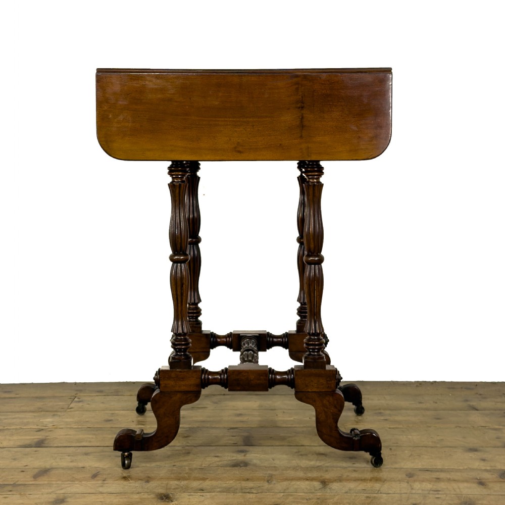 An antique Victorian dark mahogany drop-leaf work table featuring a single drawer with turned wooden knobs, fluted legs, and scroll feet on brass castors. View II
