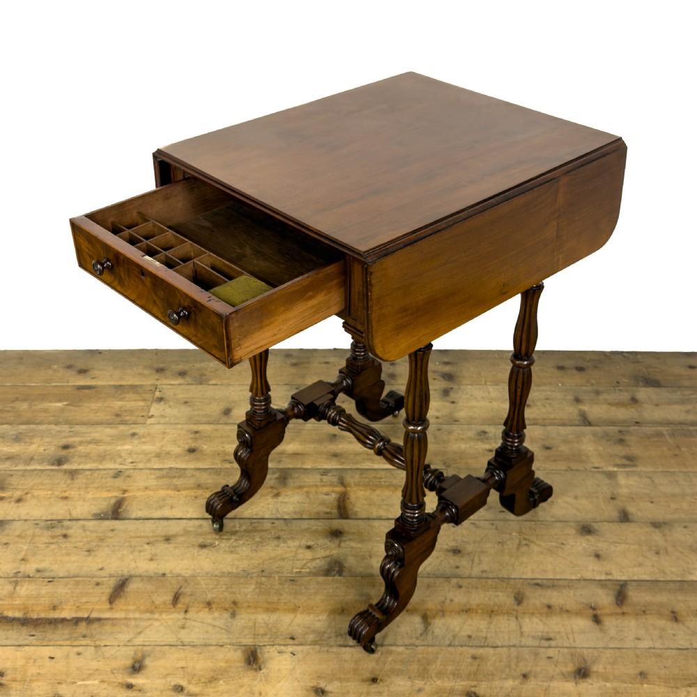 An antique Victorian dark mahogany drop-leaf work table featuring a single drawer with turned wooden knobs, fluted legs, and scroll feet on brass castors. View VI