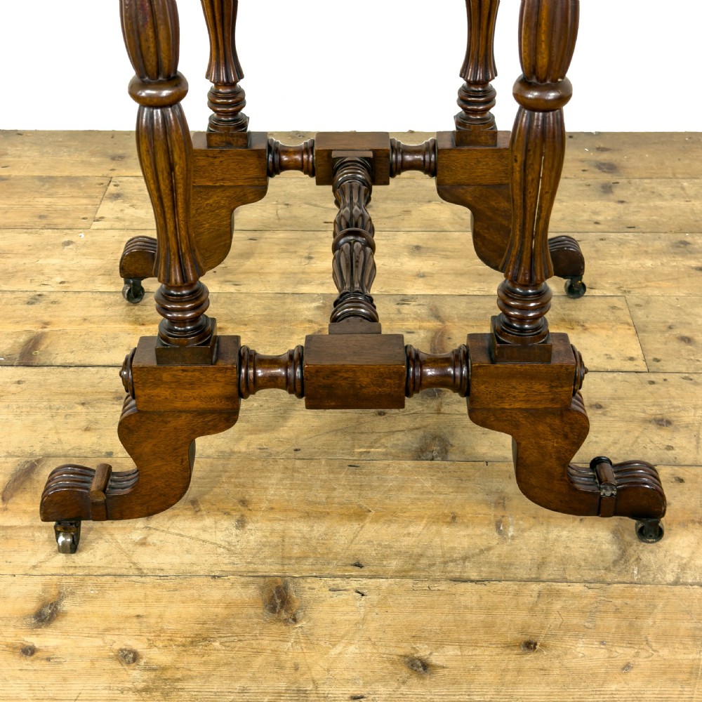 An antique Victorian dark mahogany drop-leaf work table featuring a single drawer with turned wooden knobs, fluted legs, and scroll feet on brass castors. View VIII