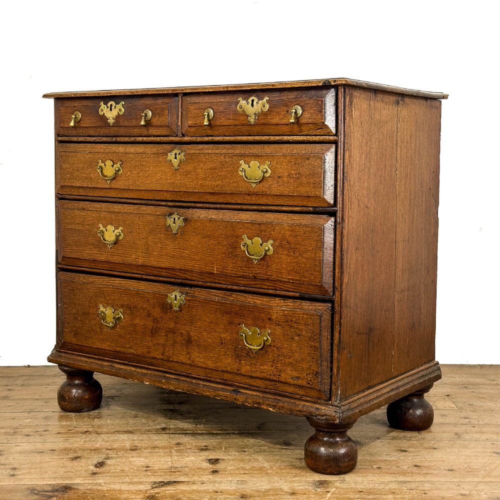 An antique 18th-century oak chest of drawers featuring a two short over three long drawer arrangement, brass handles, and turned bun feet. View II