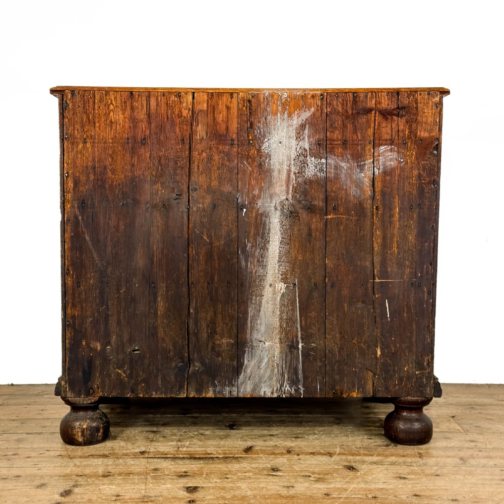 An antique 18th-century oak chest of drawers featuring a two short over three long drawer arrangement, brass handles, and turned bun feet. View V