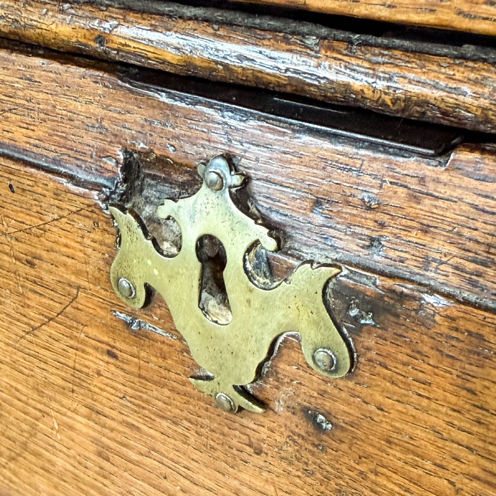 An antique 18th-century oak chest of drawers featuring a two short over three long drawer arrangement, brass handles, and turned bun feet. View IX
