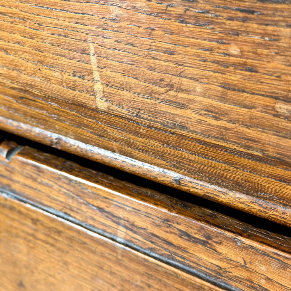An antique 18th-century oak chest of drawers featuring a two short over three long drawer arrangement, brass handles, and turned bun feet. View X