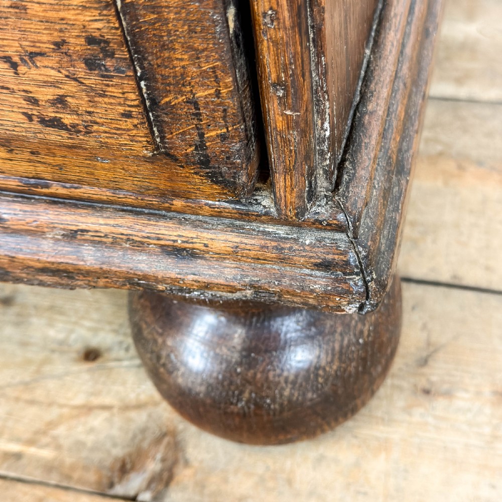 An antique 18th-century oak chest of drawers featuring a two short over three long drawer arrangement, brass handles, and turned bun feet. View XI