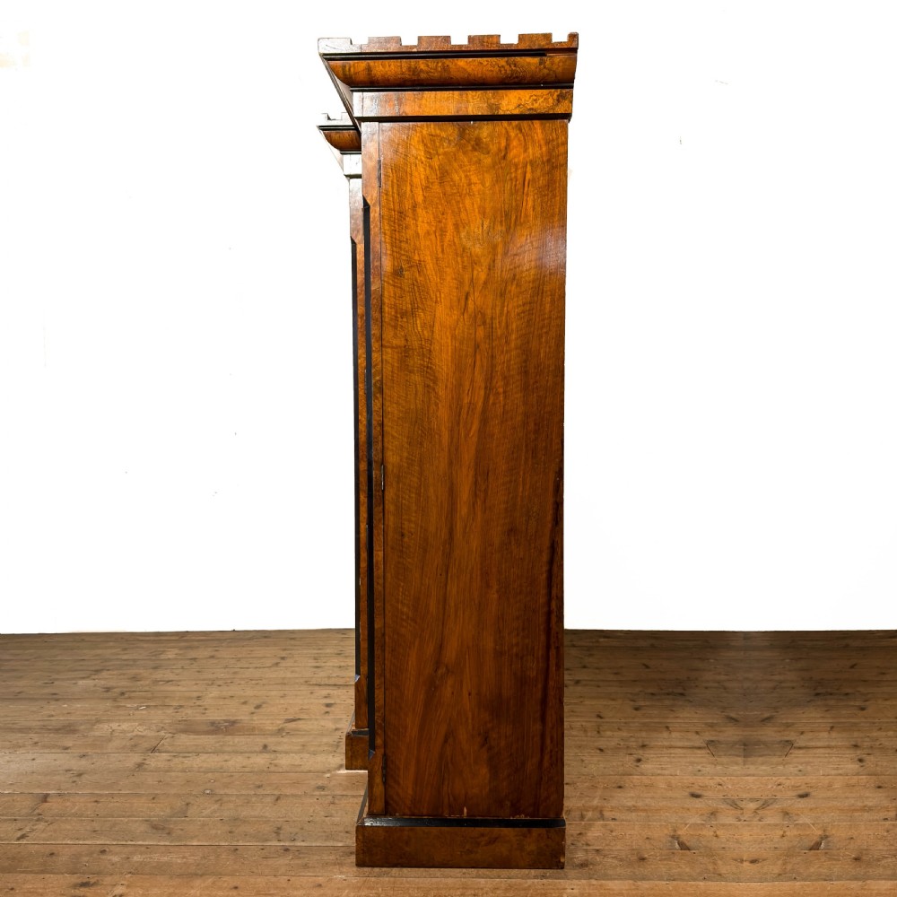 A Victorian burr walnut triple compactum wardrobe with an arched central mirrored door flanked by two panelled timber doors and topped with a castellated cornice. View VI