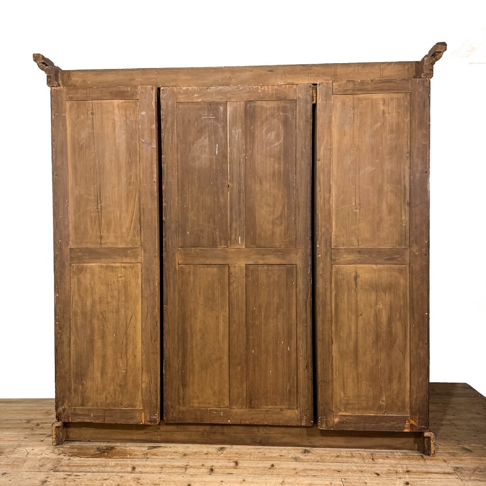 A Victorian burr walnut triple compactum wardrobe with an arched central mirrored door flanked by two panelled timber doors and topped with a castellated cornice. View VII