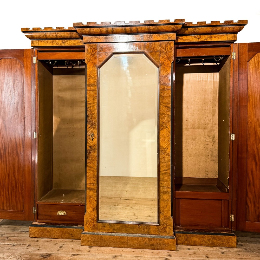 A Victorian burr walnut triple compactum wardrobe with an arched central mirrored door flanked by two panelled timber doors and topped with a castellated cornice. View XIII