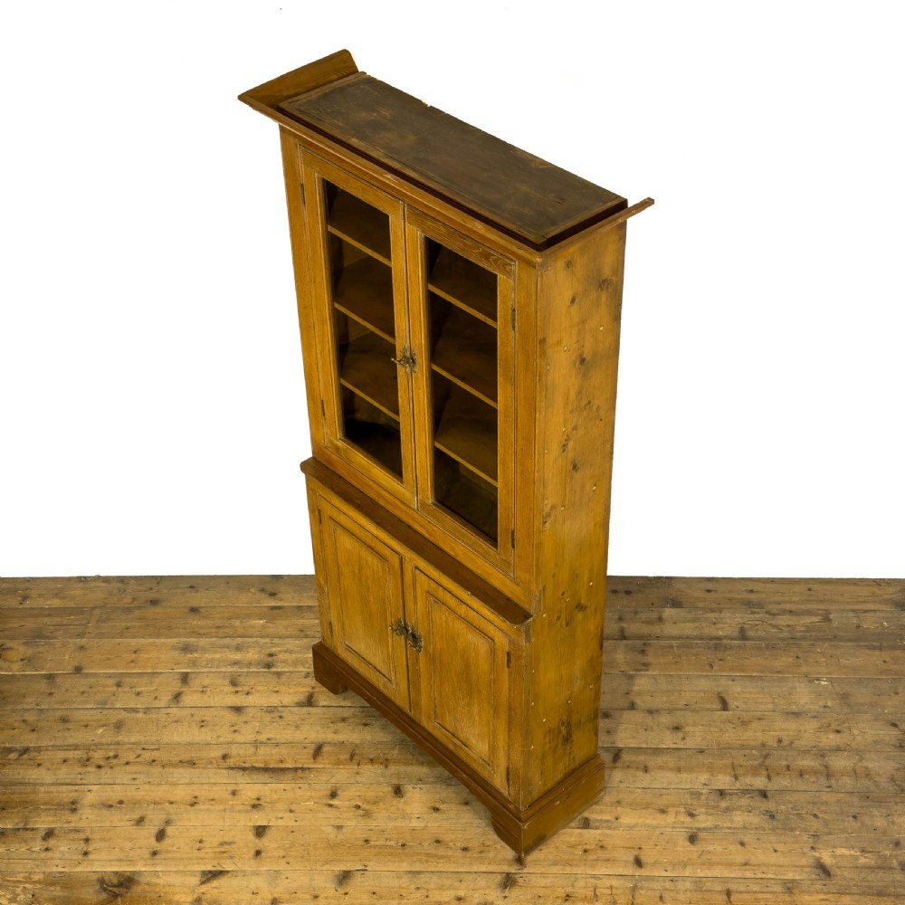 An early 20th-century golden oak cupboard featuring upper glazed double doors over lower solid panelled doors with brass hardware. View II