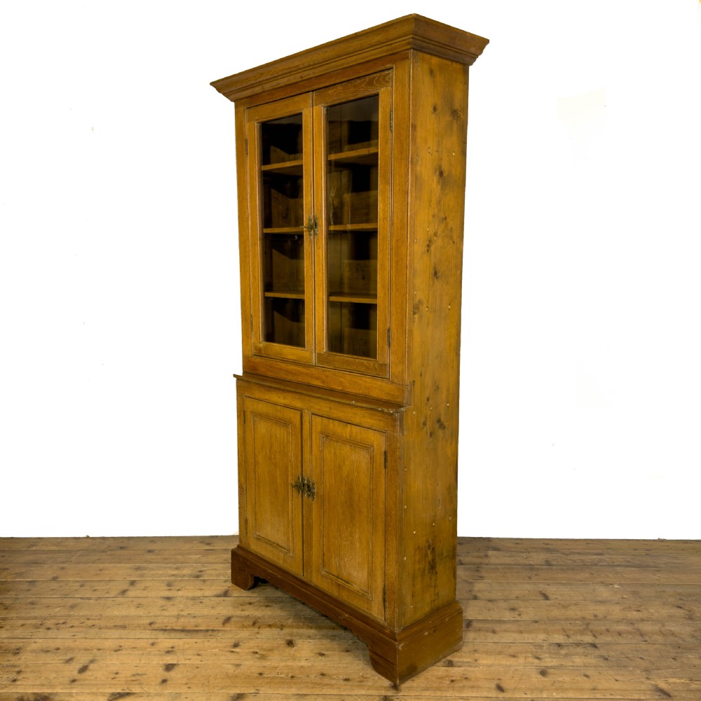 An early 20th-century golden oak cupboard featuring upper glazed double doors over lower solid panelled doors with brass hardware. View III