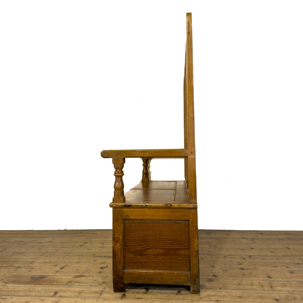 A high-backed antique pine settle bench with a four-panel backrest, turned arm supports, and a hinged seat box. View III