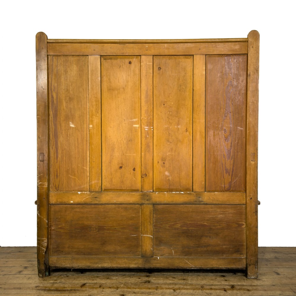 A high-backed antique pine settle bench with a four-panel backrest, turned arm supports, and a hinged seat box. View IV