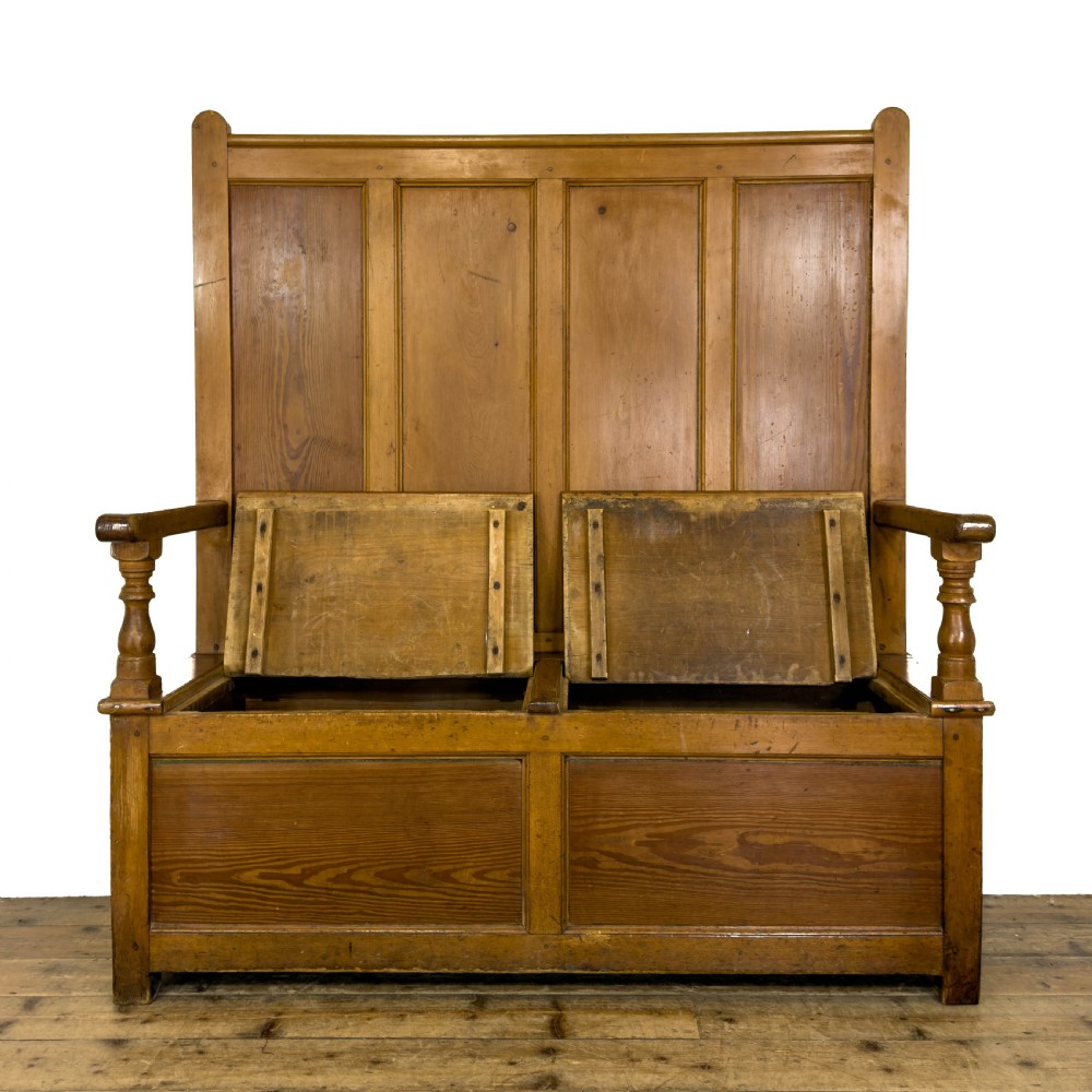 A high-backed antique pine settle bench with a four-panel backrest, turned arm supports, and a hinged seat box. View VI