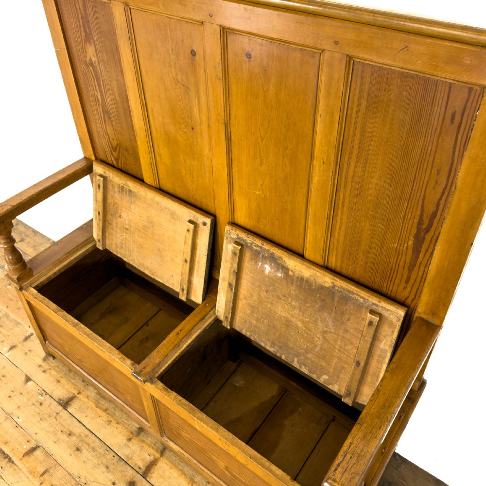 A high-backed antique pine settle bench with a four-panel backrest, turned arm supports, and a hinged seat box. View VII