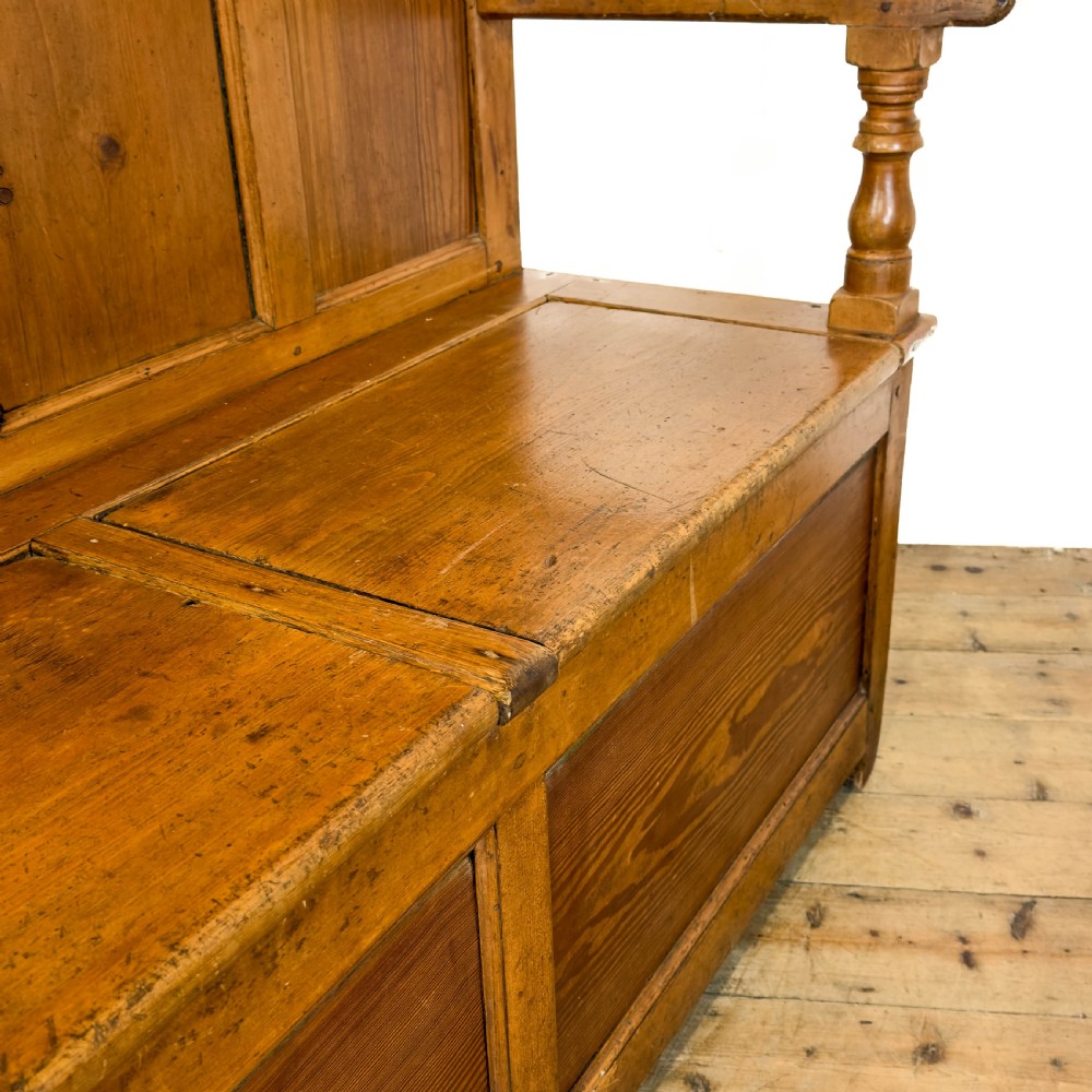 A high-backed antique pine settle bench with a four-panel backrest, turned arm supports, and a hinged seat box. View IX