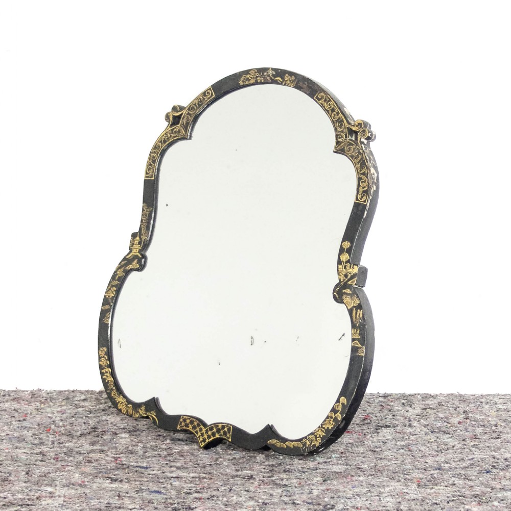 An antique ebonised table mirror featuring a scalloped frame decorated with gold hand-painted chinoiserie motifs.