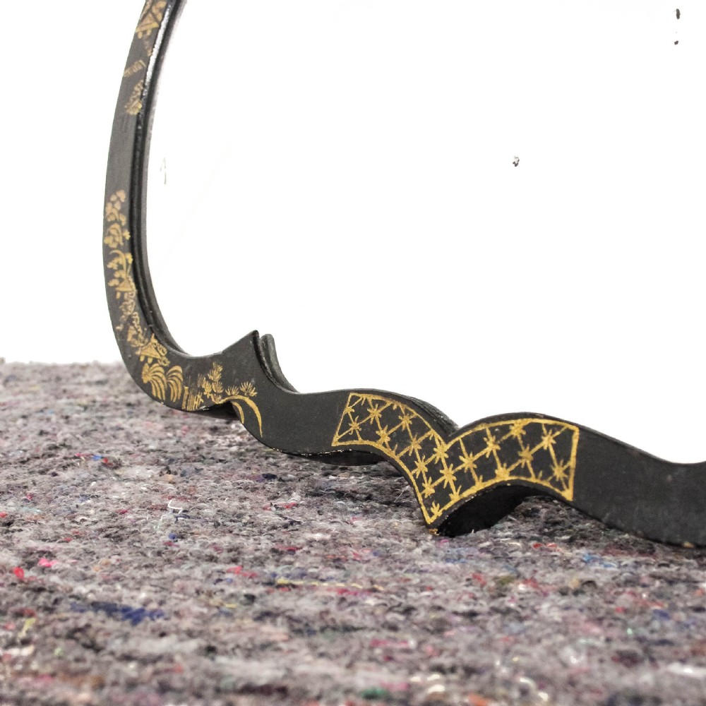 An antique ebonised table mirror featuring a scalloped frame decorated with gold hand-painted chinoiserie motifs. View IV