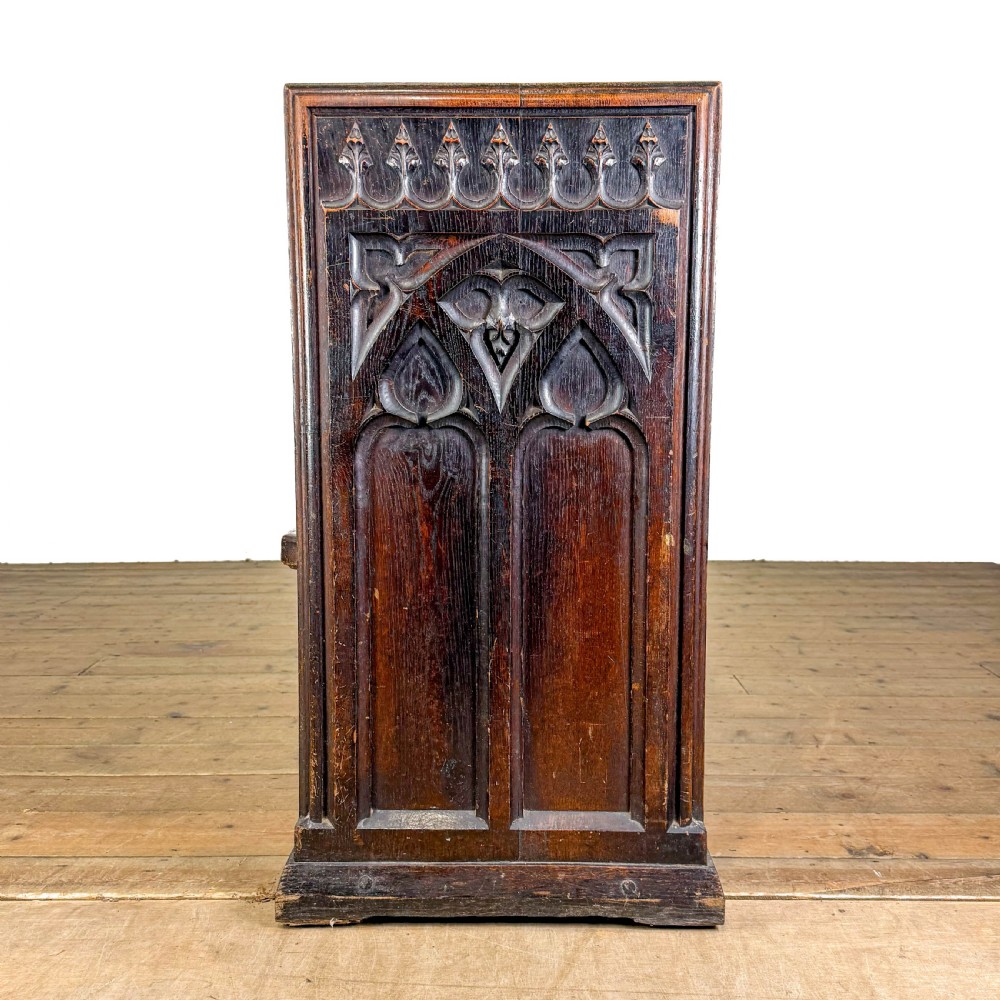 A long 19th-century oak church pew featuring carved Gothic tracery on its end panel and an open frame back. View III