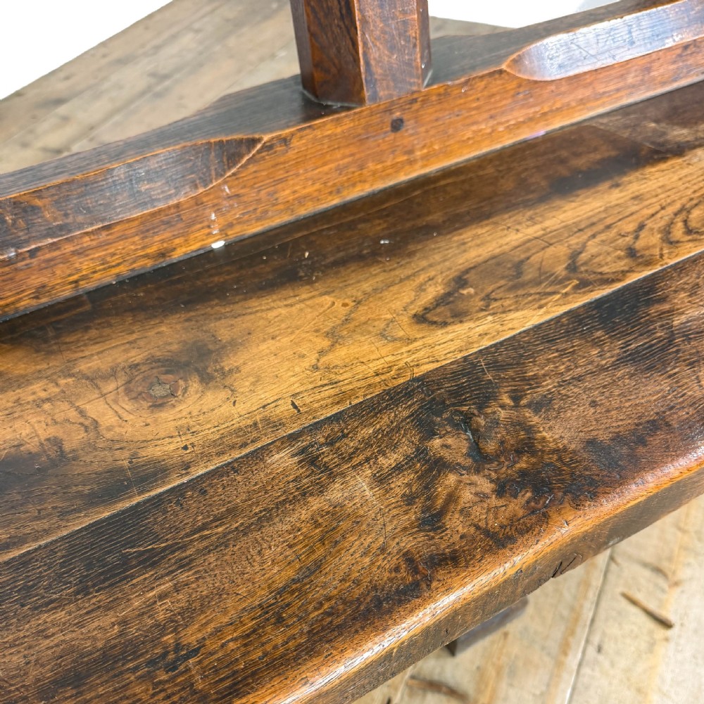 A long 19th-century oak church pew featuring carved Gothic tracery on its end panel and an open frame back. View IV