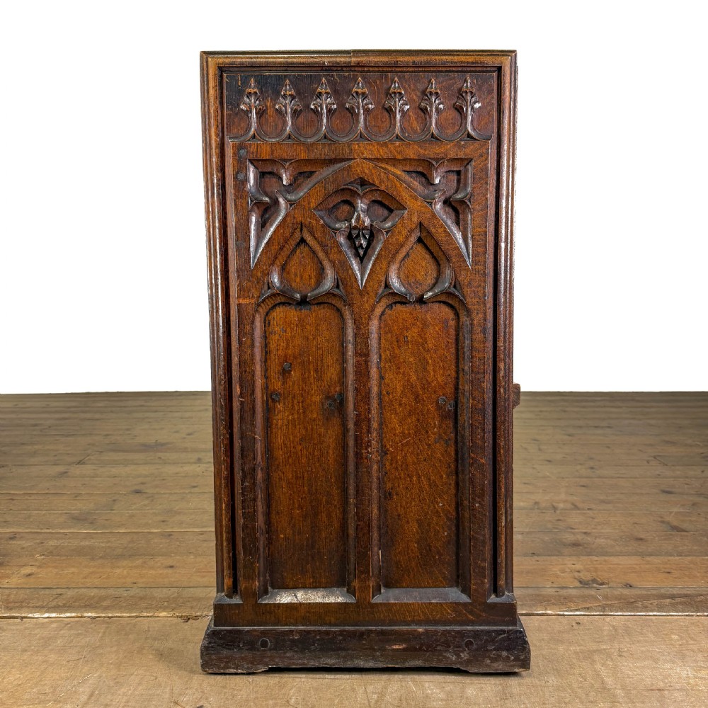 A long 19th-century oak church pew featuring carved Gothic tracery on its end panel and an open frame back. View V