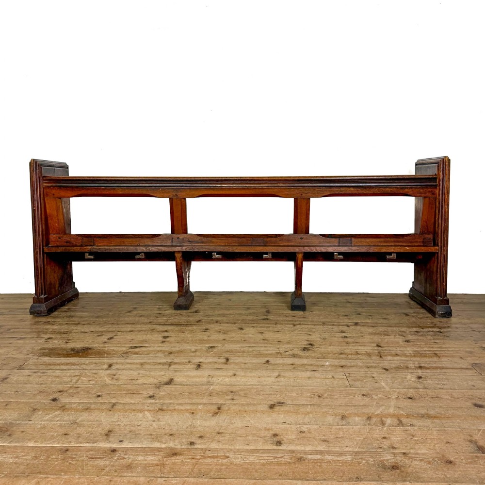 A long 19th-century oak church pew featuring carved Gothic tracery on its end panel and an open frame back. View IX