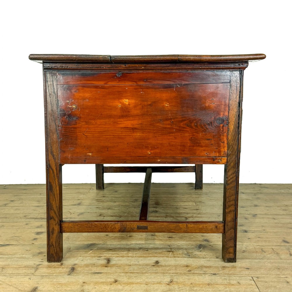 An antique oak serving table featuring brass drop handles, multiple drawer compartments, a scalloped apron, and straight legs connected by stretchers. View V