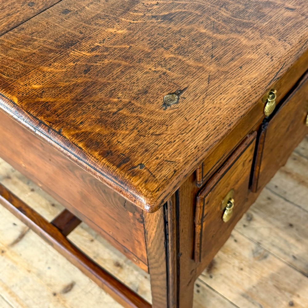 An antique oak serving table featuring brass drop handles, multiple drawer compartments, a scalloped apron, and straight legs connected by stretchers. View VI