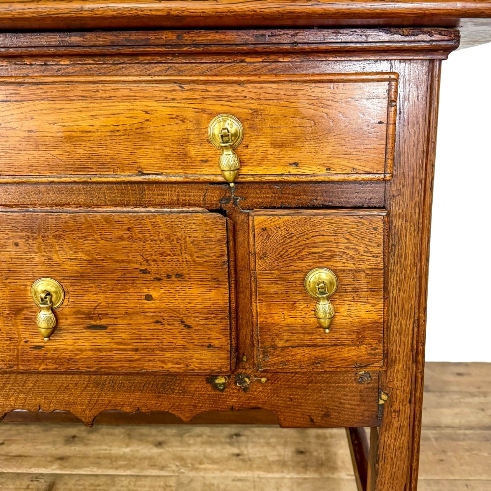 An antique oak serving table featuring brass drop handles, multiple drawer compartments, a scalloped apron, and straight legs connected by stretchers. View VII