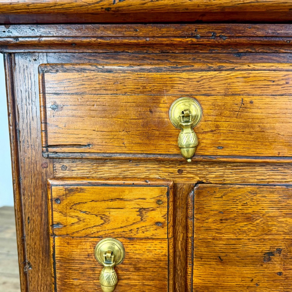 An antique oak serving table featuring brass drop handles, multiple drawer compartments, a scalloped apron, and straight legs connected by stretchers. View IX