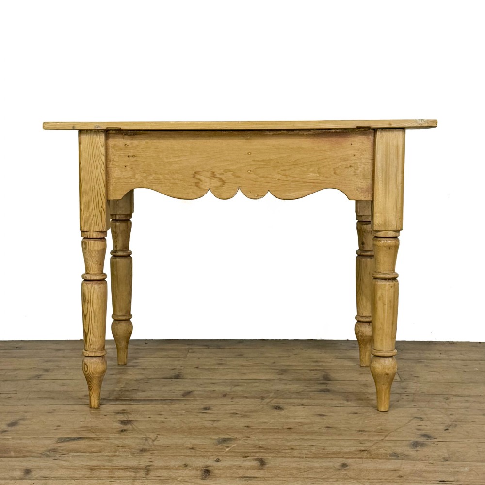 An antique honey pine kitchen table featuring hand-turned legs, a scalloped apron, and a single end drawer with a dark turned wooden knob. View II