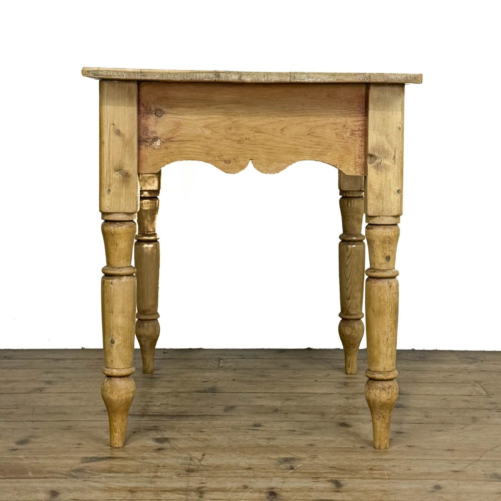 An antique honey pine kitchen table featuring hand-turned legs, a scalloped apron, and a single end drawer with a dark turned wooden knob. View III