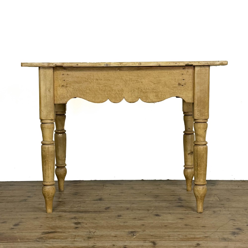 An antique honey pine kitchen table featuring hand-turned legs, a scalloped apron, and a single end drawer with a dark turned wooden knob. View IV