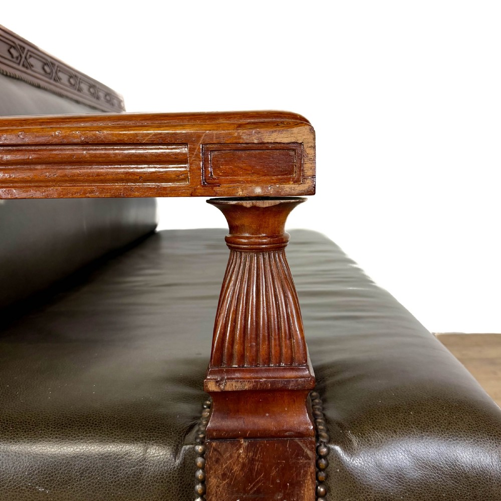 Late nineteenth-century carved oak hall settle featuring olive green leather upholstery with brass stud trim and turned legs. View VI
