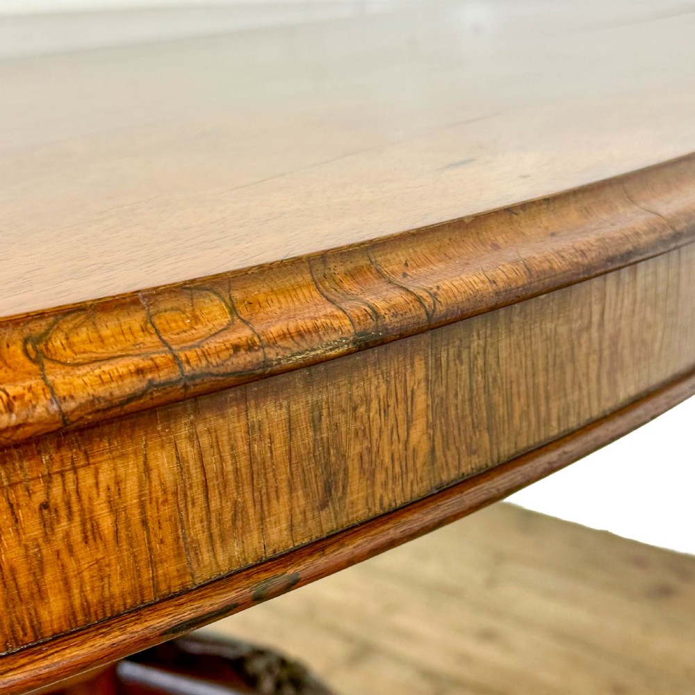 A circular nineteenth-century rosewood loo table supported by a turned central pedestal and four carved scroll legs on castors. View VIII