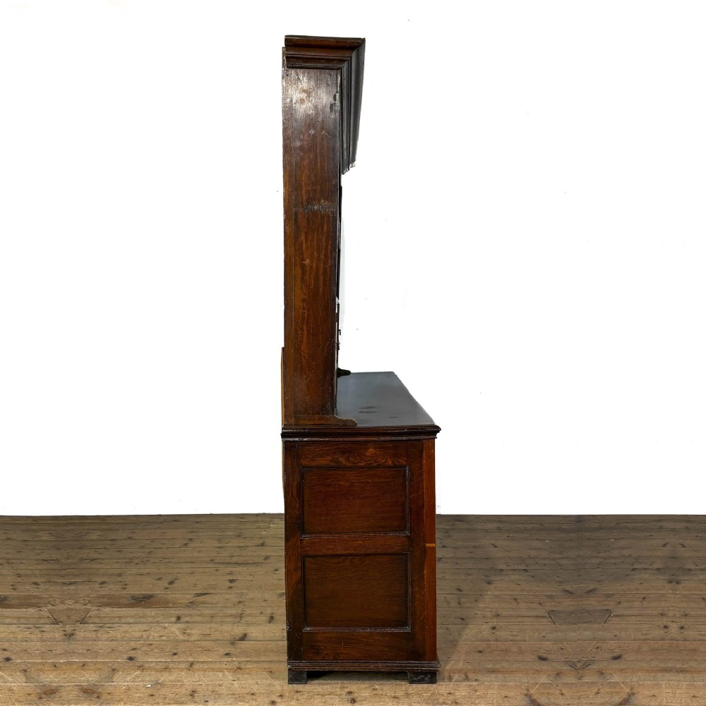 An antique Georgian dark oak dresser featuring an upper shelving rack, small cupboard doors with diamond inlay, and a base containing multiple drawers and panelled cupboards with brass handles. View VIII