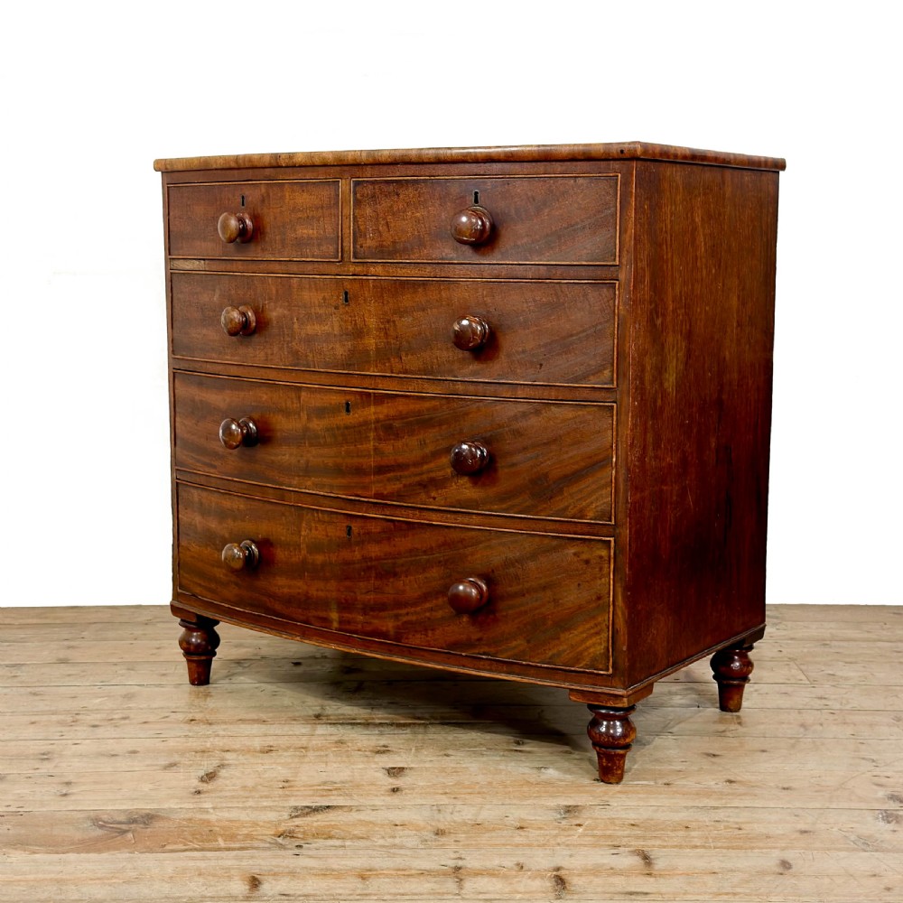 An antique mahogany bow front chest of drawers with two short drawers over three long graduated drawers, turned wooden handles, and turned feet. View II